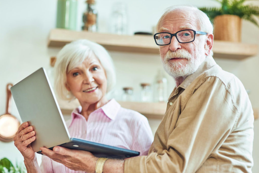 Un couple de personnes âgées porte un ordinateur portable