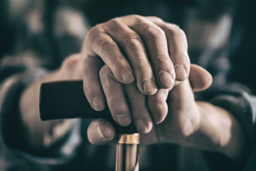Mains d'une personne âgée posées sur une canne