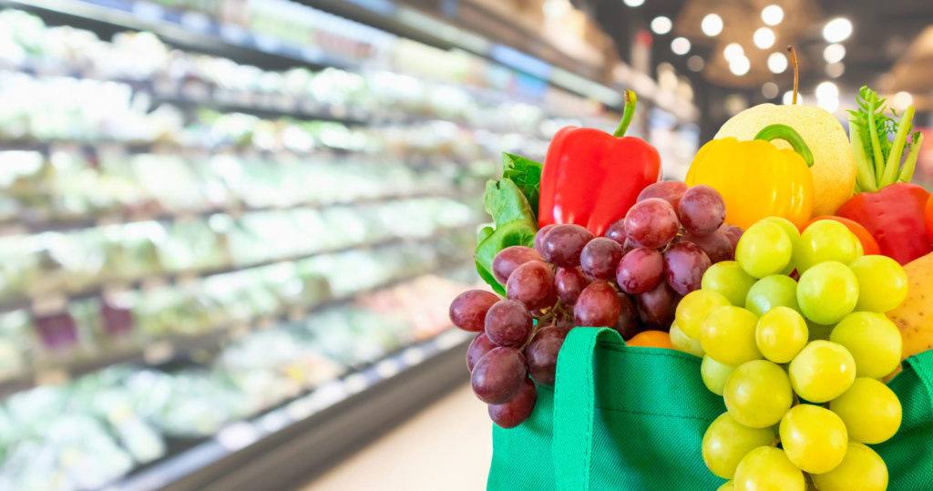des fruits et légumes dans un sac en toile sur un fond flou de supermarché