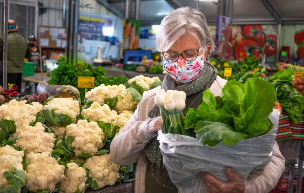 Une Femme âgée Avec Un Masque Regarde Ses Achats De Légumes Au Marché