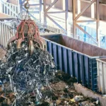 Alat berat mengangkat tumpukan scrap logam di fasilitas daur ulang